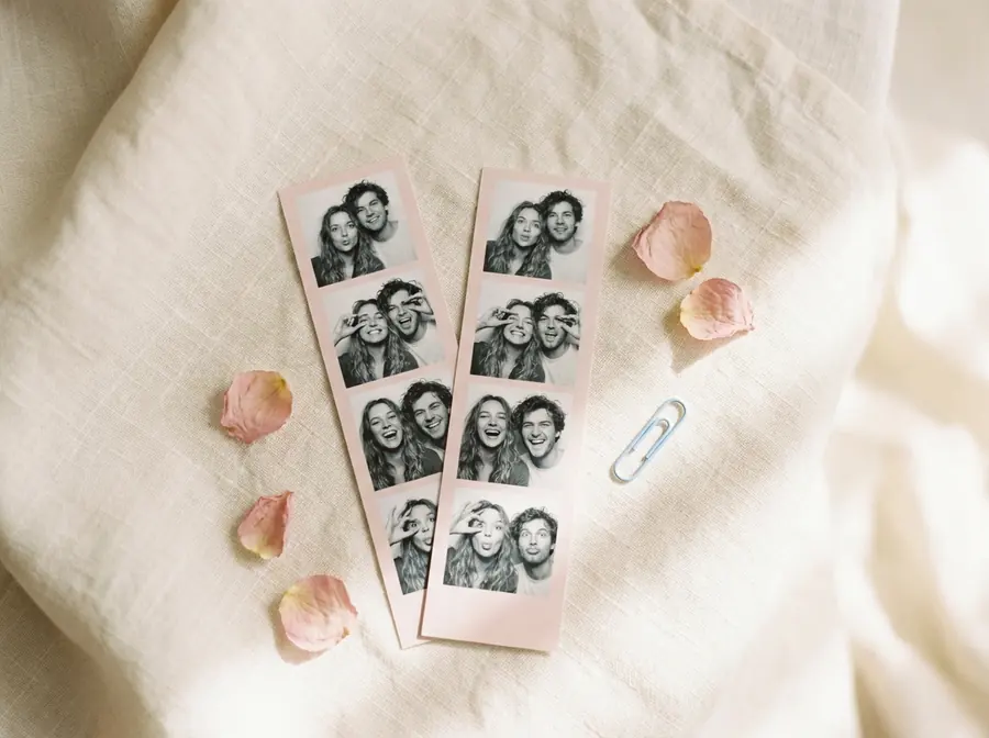 Two printed photo booth strips of a couple pulling faces, on cream linen.
