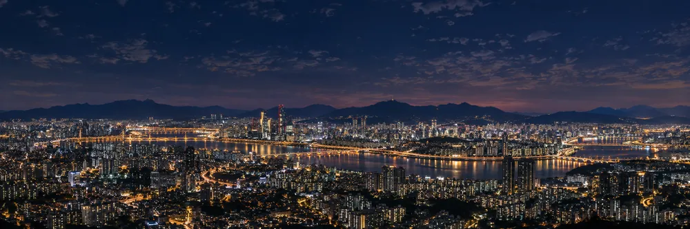 The illuminated Seoul skyline and Han River at night.